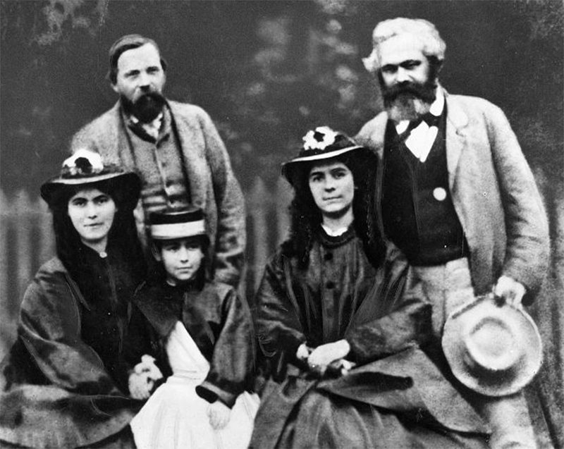 Karl Marx with his daughters standing next to Friedrich Engels