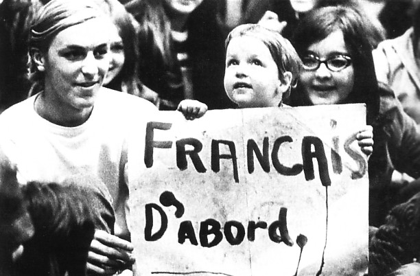 A child carrying a sign saying: French First
